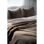Brown bedding with pillows on a bed in a softly lit room