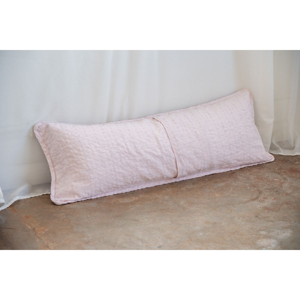 Two pink pillows on a textured surface with a light curtain background
